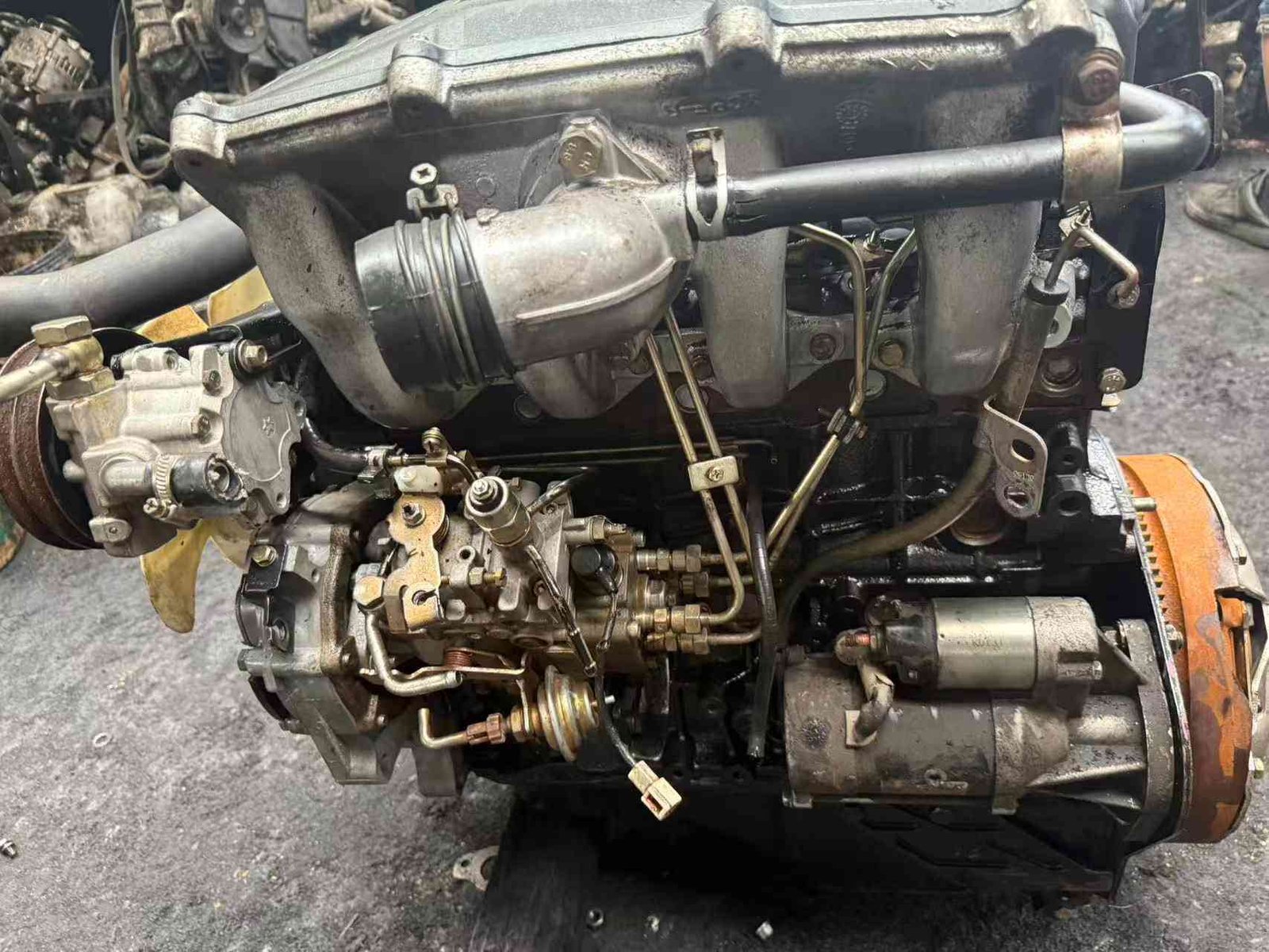 Isuzu 4JB1 direct injection engine top view with valve cover and AC compressor