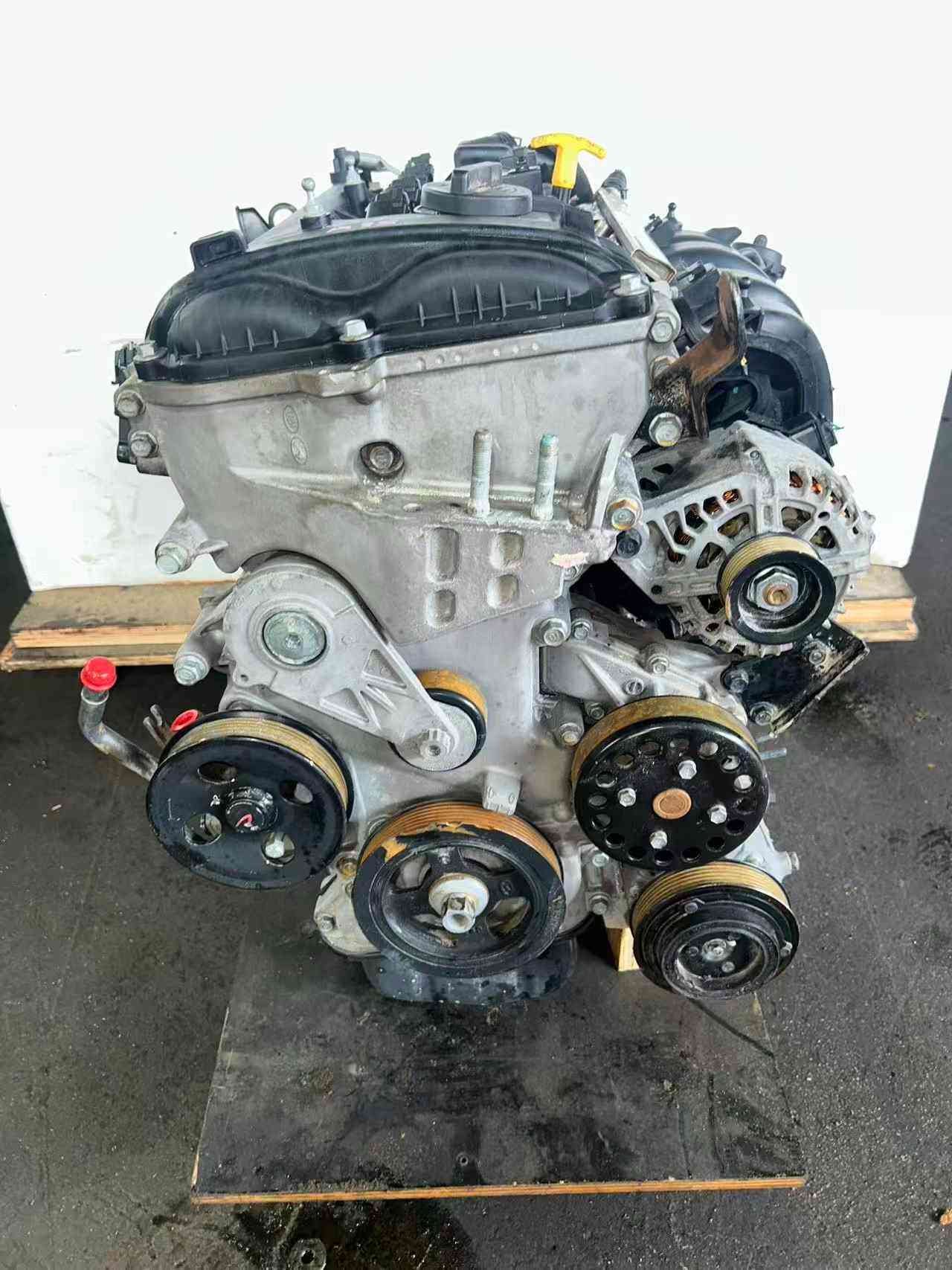 Genuine used Hyundai Elantra 1.8L Nu engine (G4NB) valve cover and pulley side view for sale - grooved pulleys and red hose fittings