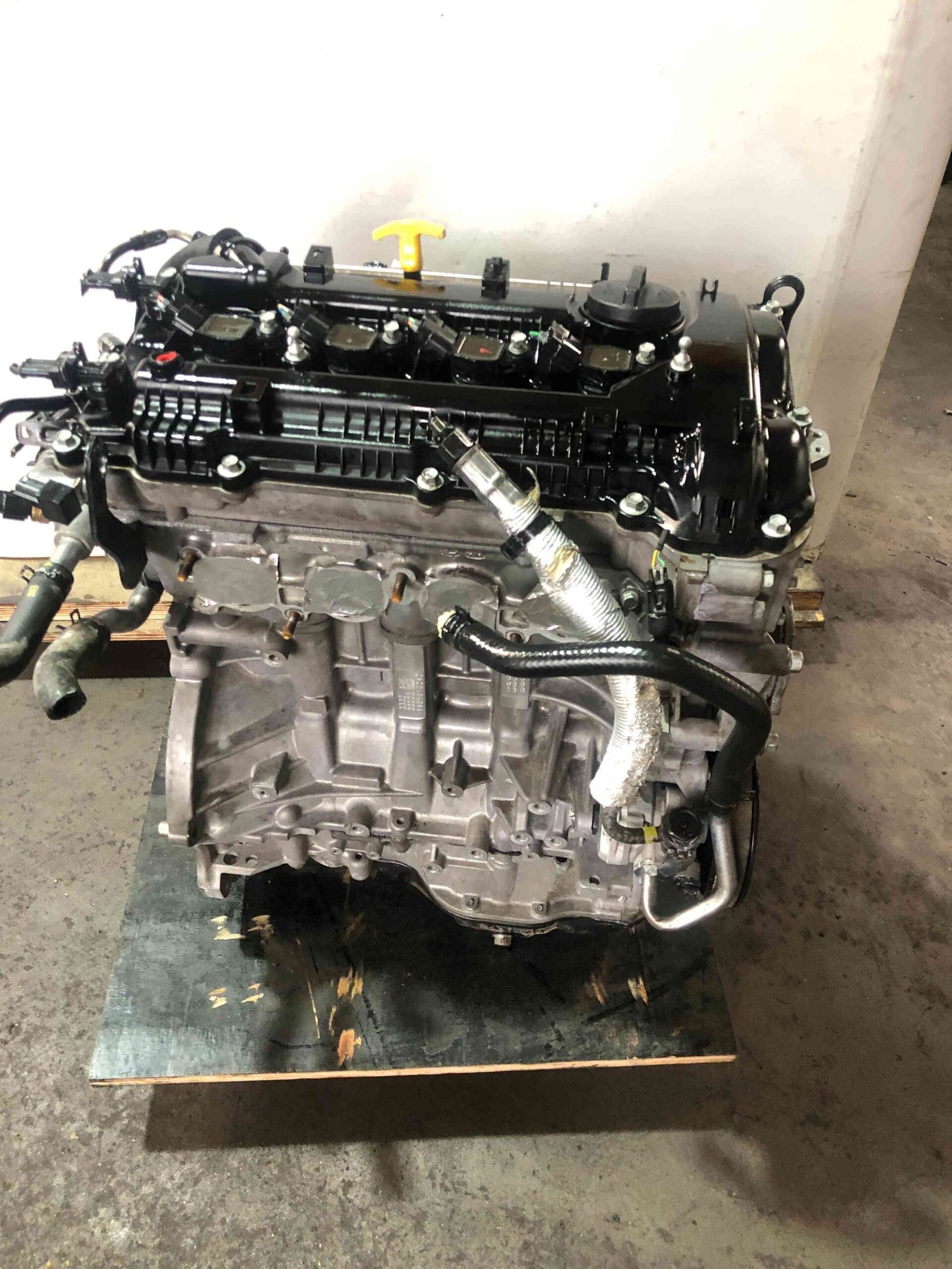 Genuine used Hyundai Elantra 2.0L Nu engine (G4NA) valve cover and ignition coil close-up for sale - block markings visible