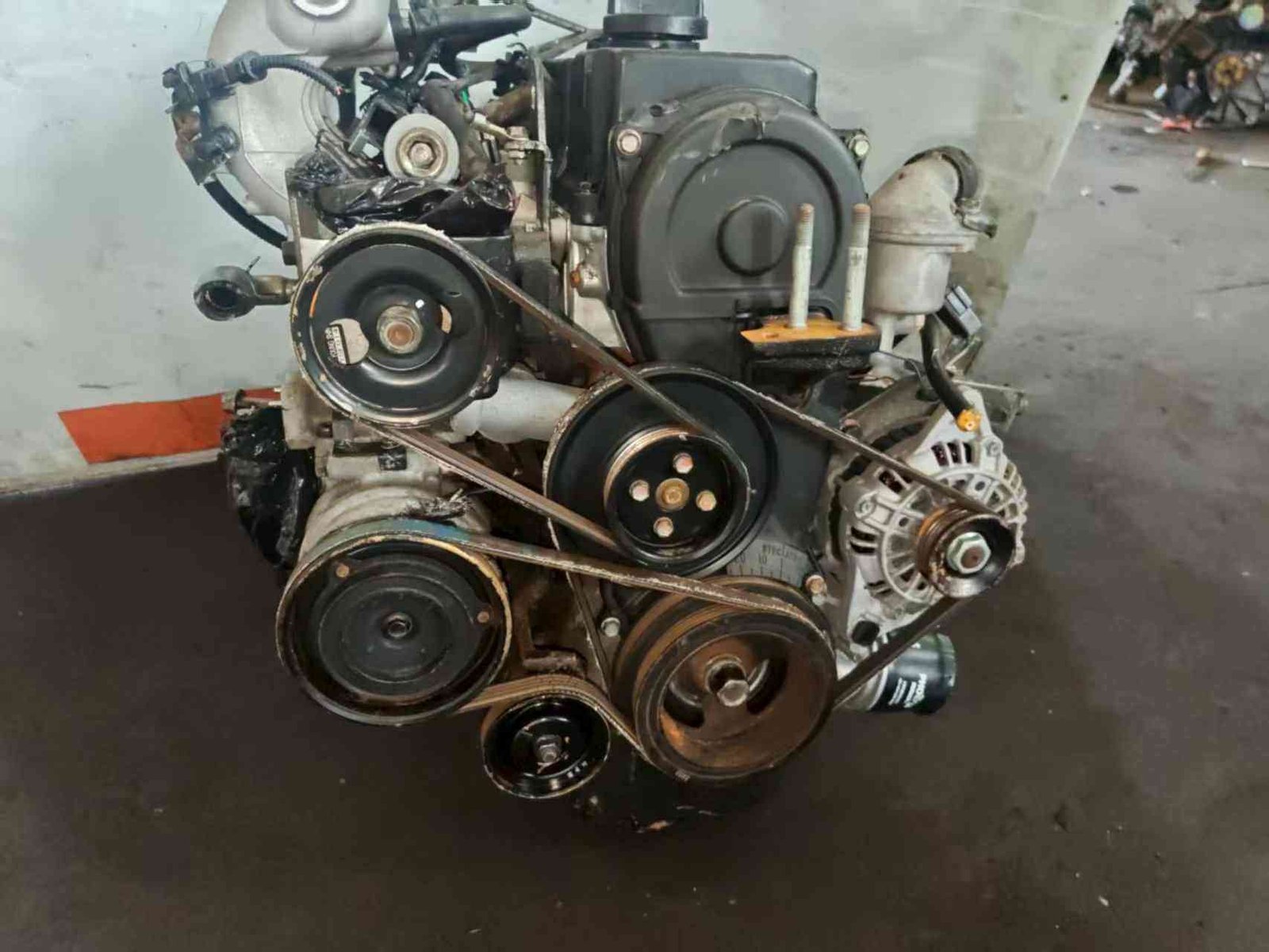 Hyundai Kia G4EA used engine front view with timing cover, belts and accessory pulleys