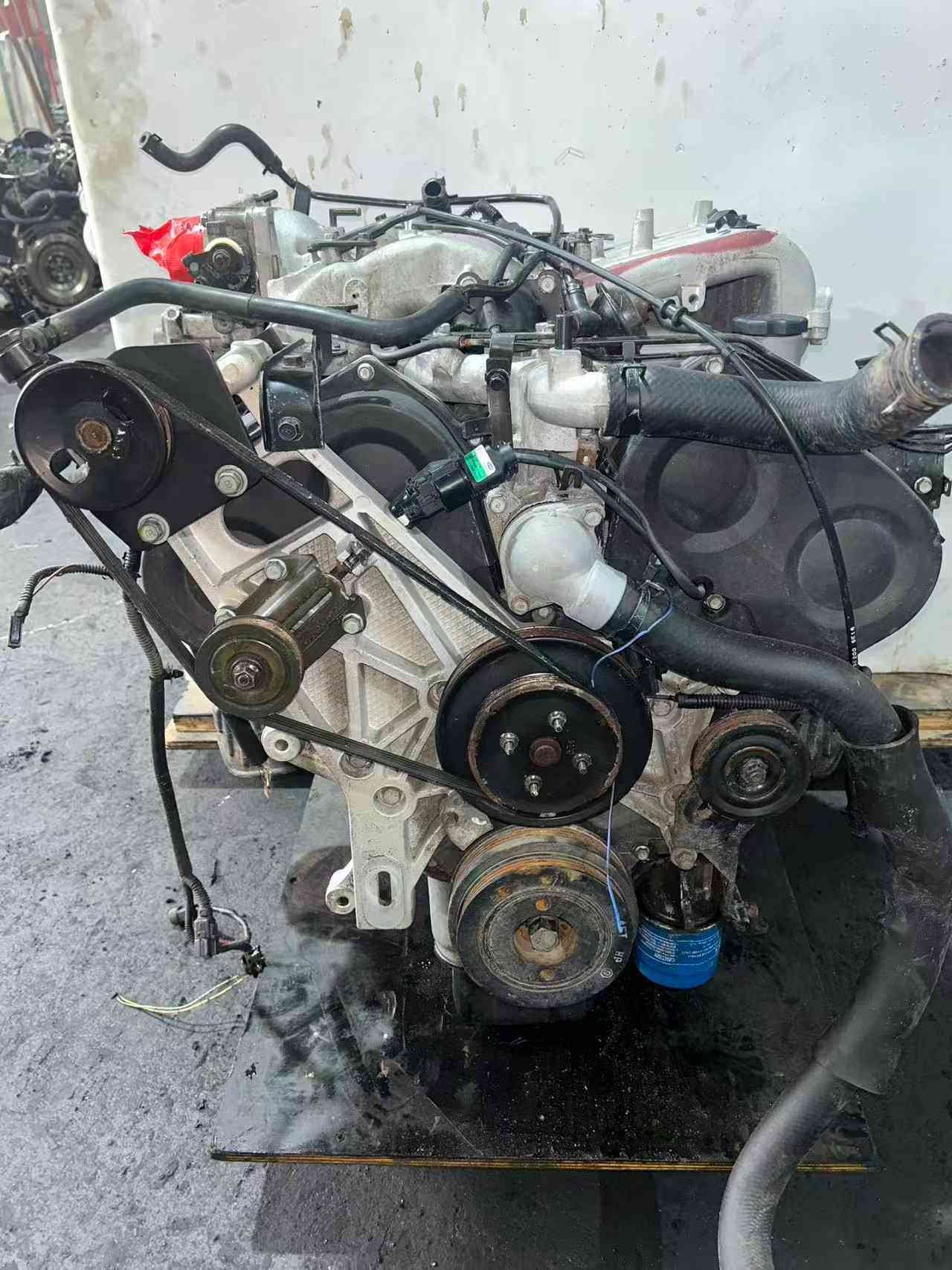 Hyundai Kia G6CU used engine front view with timing cover, belts and accessory pulleys