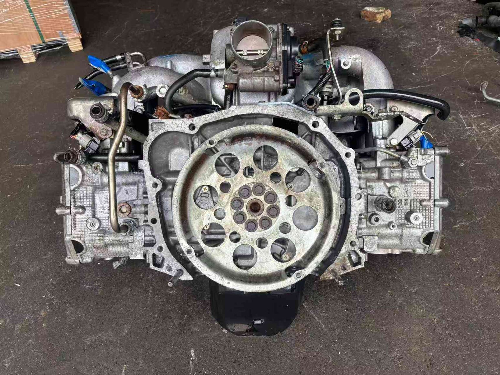 Subaru EJ20 engine assembly rear view showing flywheel mounting plate, throttle body and intake manifold