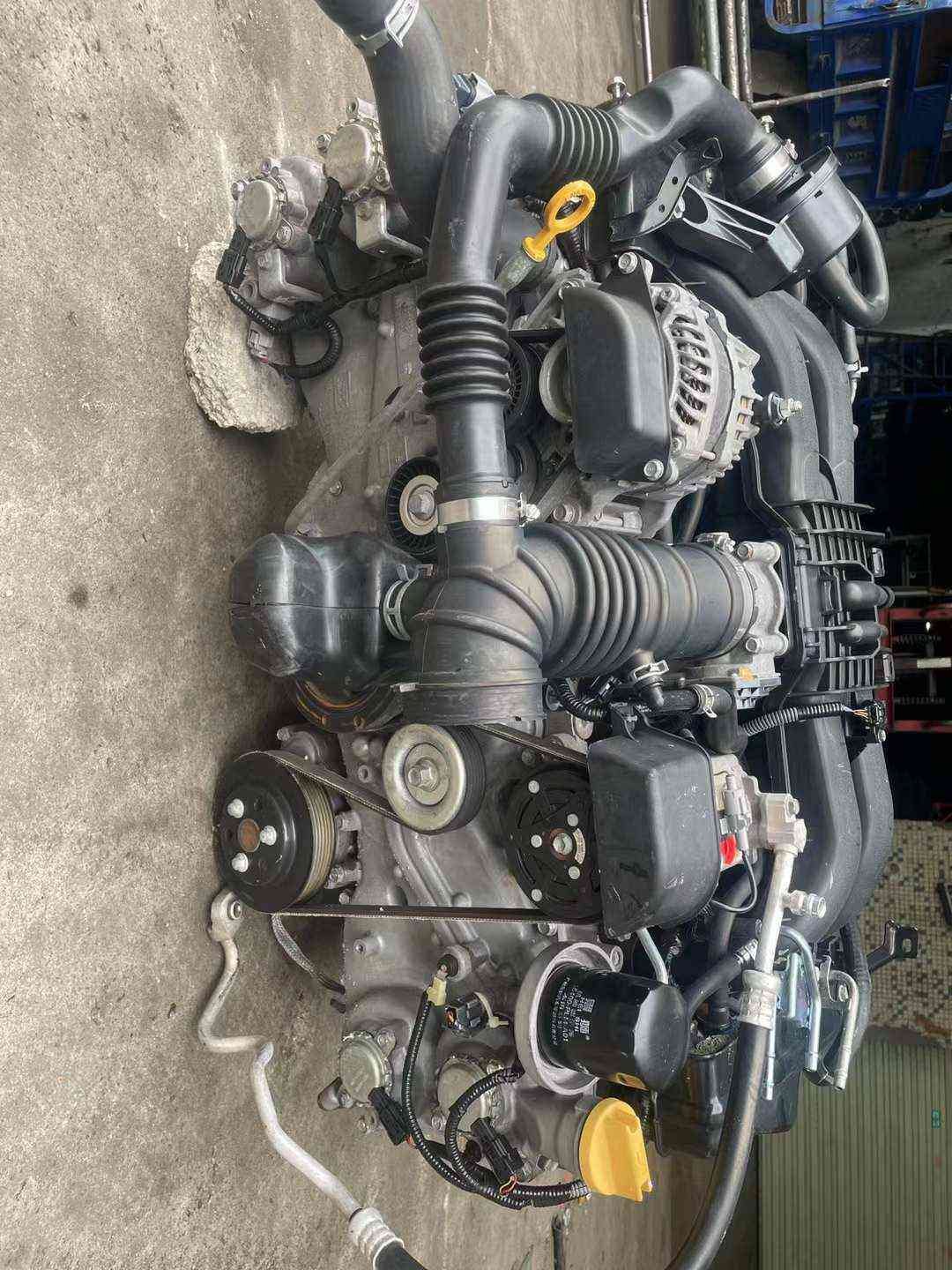 Subaru FA20 naturally aspirated engine assembly front view with alternator, intake tubing and accessory belt drive