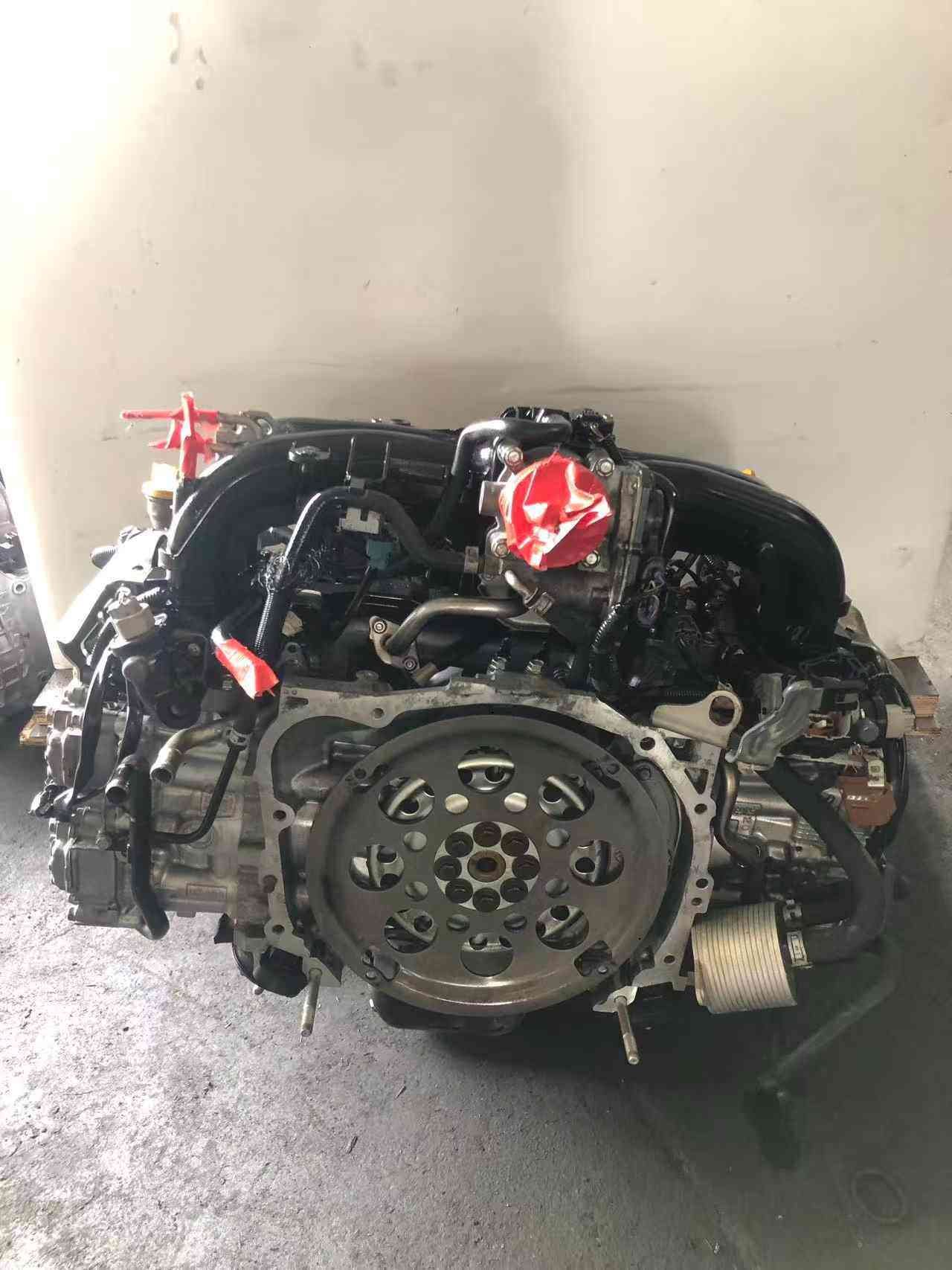 Subaru FB20 engine assembly rear view showing flywheel mounting plate, intake manifold and engine wiring