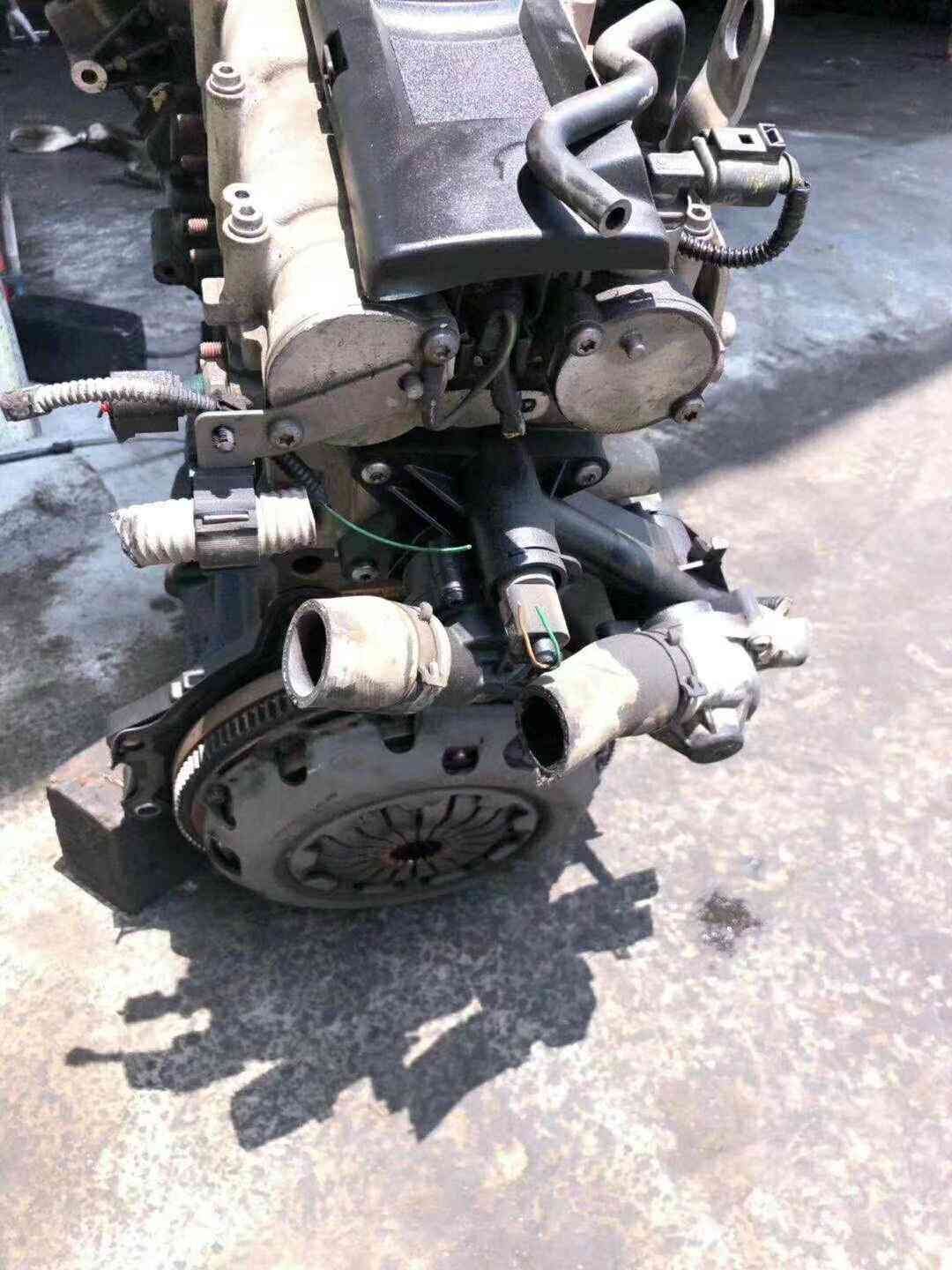 Volkswagen EA111 CDE engine assembly viewed from the clutch side with intake hoses and flywheel visible.