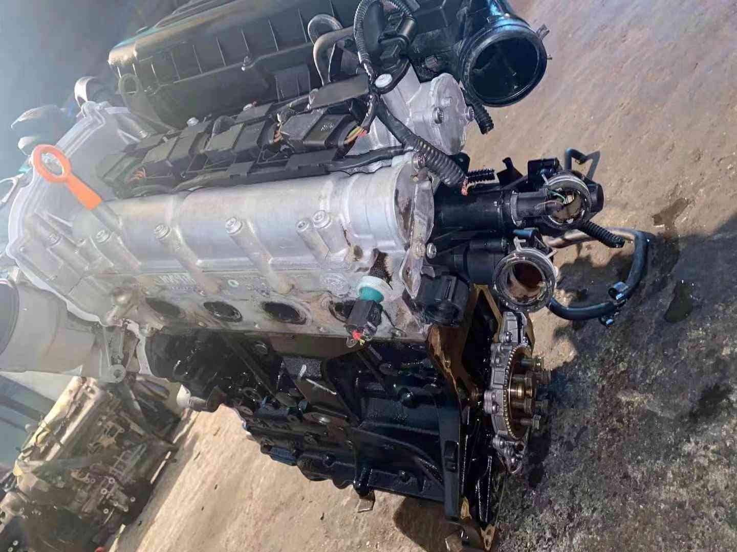 Top-side view of a Volkswagen EA111 CDE engine showing the intake manifold, wiring harness, and orange oil dipstick.