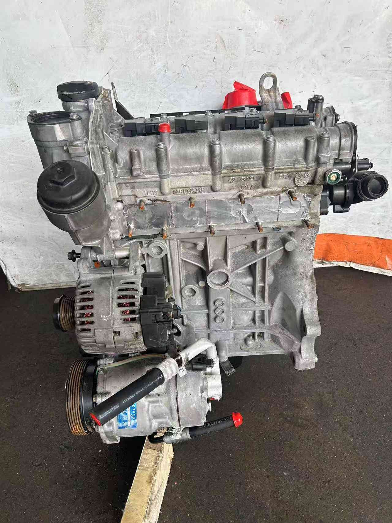 Exhaust-side view of a Volkswagen EA111 CLP engine with cylinder head, oil filter housing, alternator, and accessory pulleys.