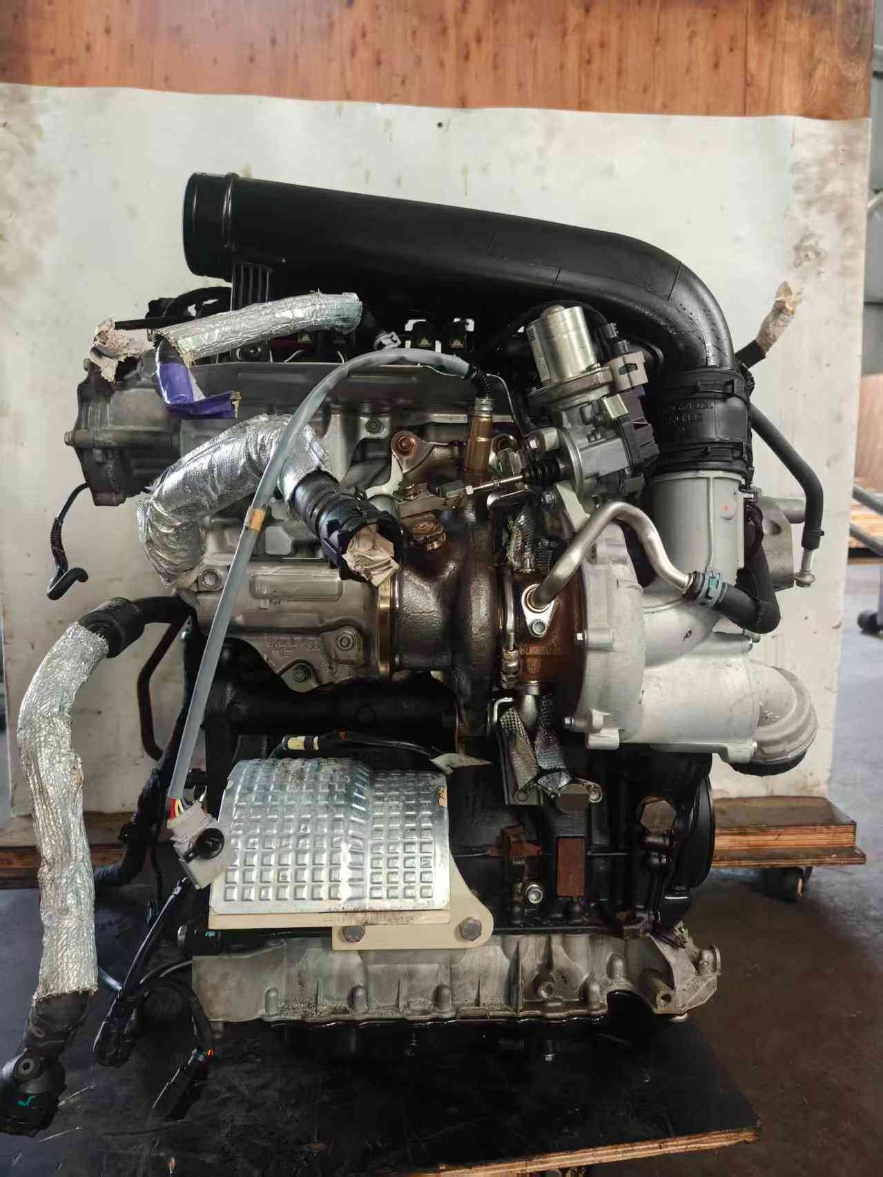 Turbocharger-side view of a Volkswagen EA888 Gen 3 CHH engine with turbo housing, intake duct, and heat-shielded exhaust piping.