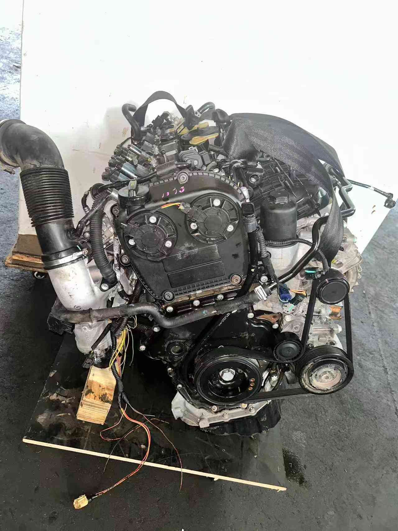 Timing-cover view of a Volkswagen EA888 Gen 3 CJE engine with camshaft cover, crank pulley, and accessory belt.